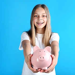 a patient with braces holding a piggy bank in Lake Nona