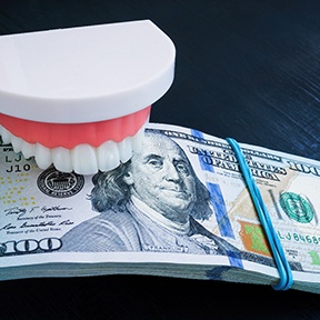 a plastic model of a mouth holding a stack of money