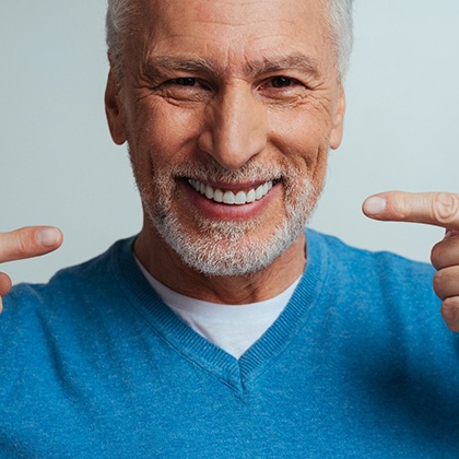 An older man pointing at his new implant denture