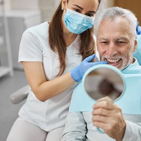 a patient checking his new dental implants with a mirror