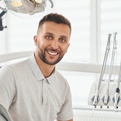 Bearded male dental patient leaning forward and smiling