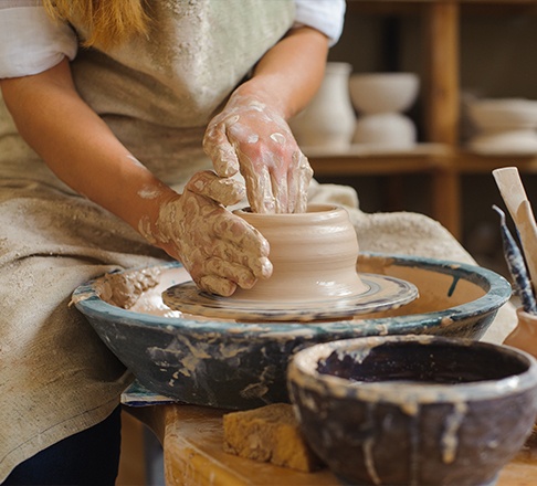 Person shaping clay pottery