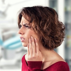 Woman with jaw pain holding jaw
