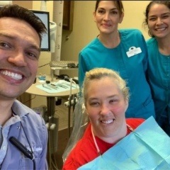 Three team members and patient smiling in dental treatment room