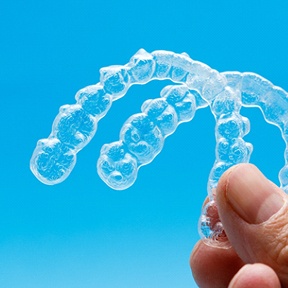 person holding two Invisalign aligners