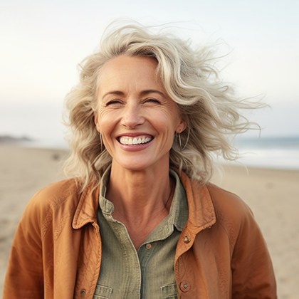 Woman smiling on the beach after a smile makeover