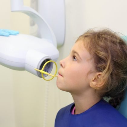 Child receiving x-rays at preventive dentistry checkup and teeth cleaning visit