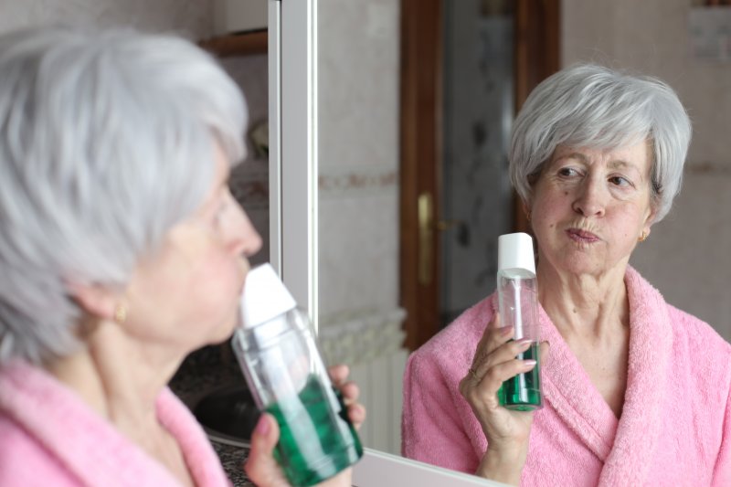Older woman using mouthwash to try to freshen her dentures